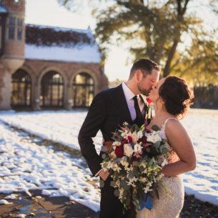 A young couple kiss in the snow on their wedding day outside of Meadow Brook Hall.