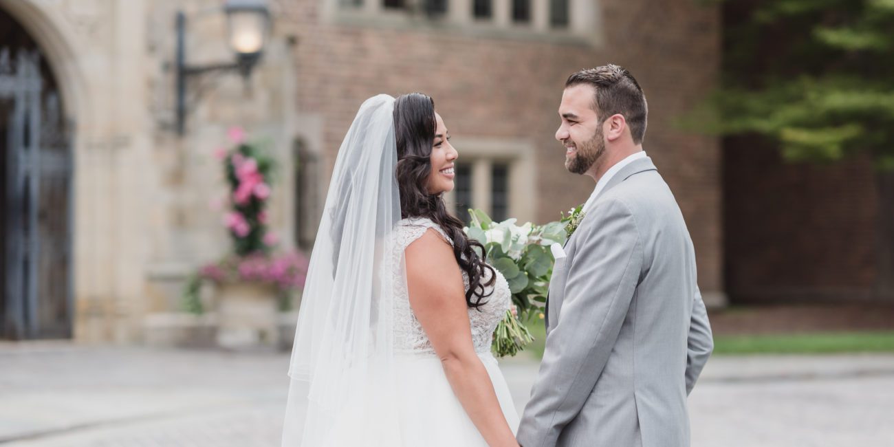 Bride and Groom hold hands and smile outside Meadow Brook Hall in summer