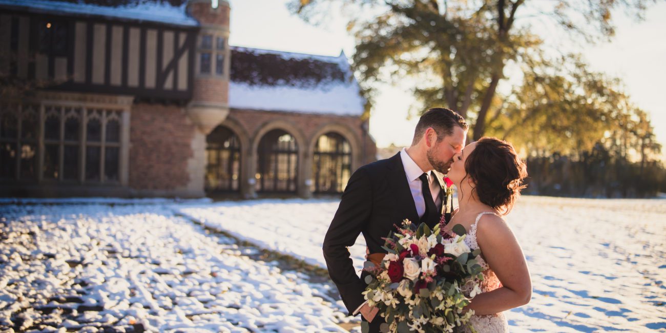Bride and Groom kiss outside Meadow Brook Hall in the snow.