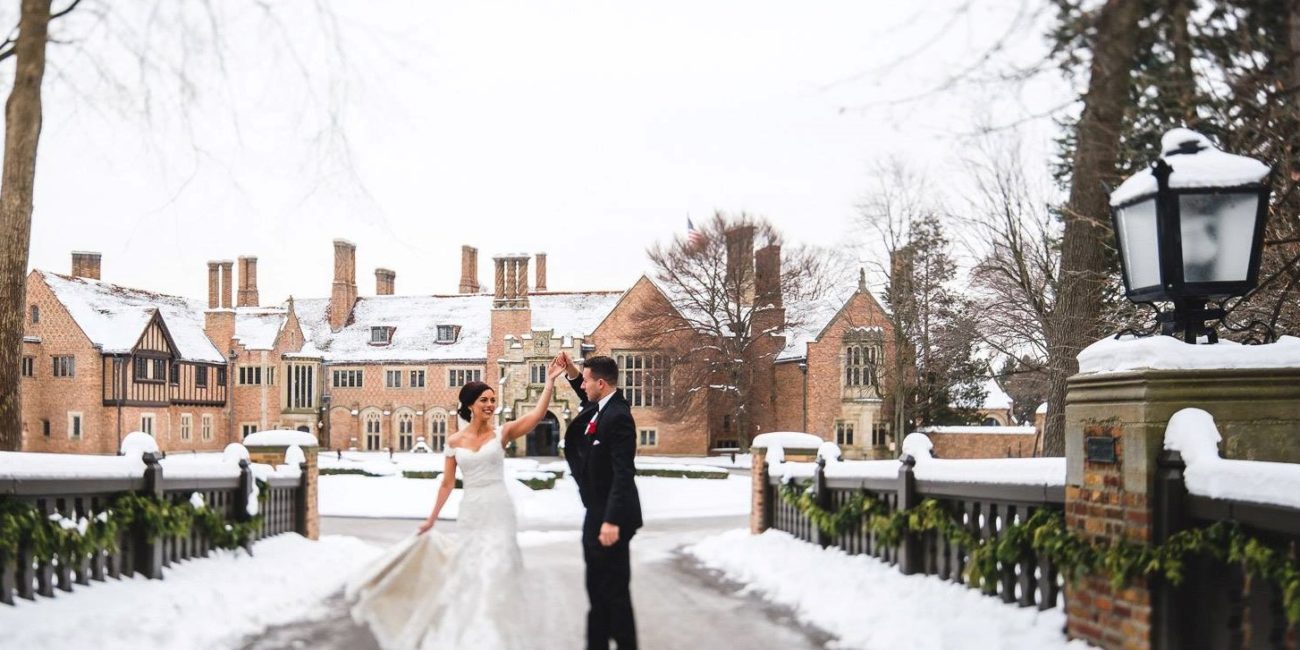 Bride and Groom stand on bridge at Meadow Brook Hall in winter.