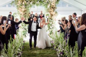 Bride and Groom come down a floral-filled aisle following their ceremony.