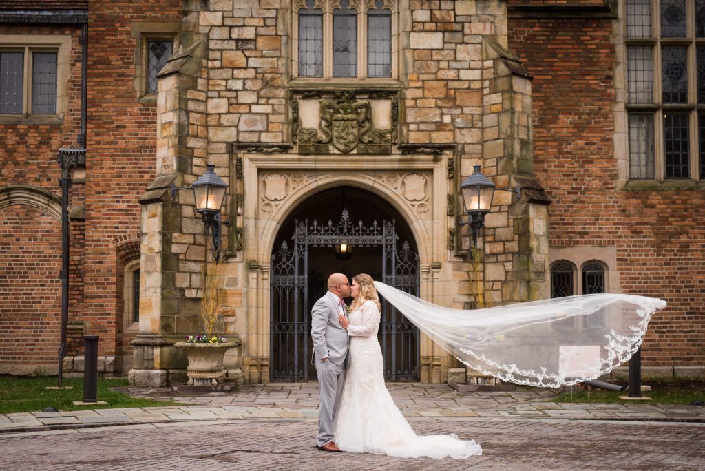 Couple poses in front of Meadow Brook's front gates on their wedding day