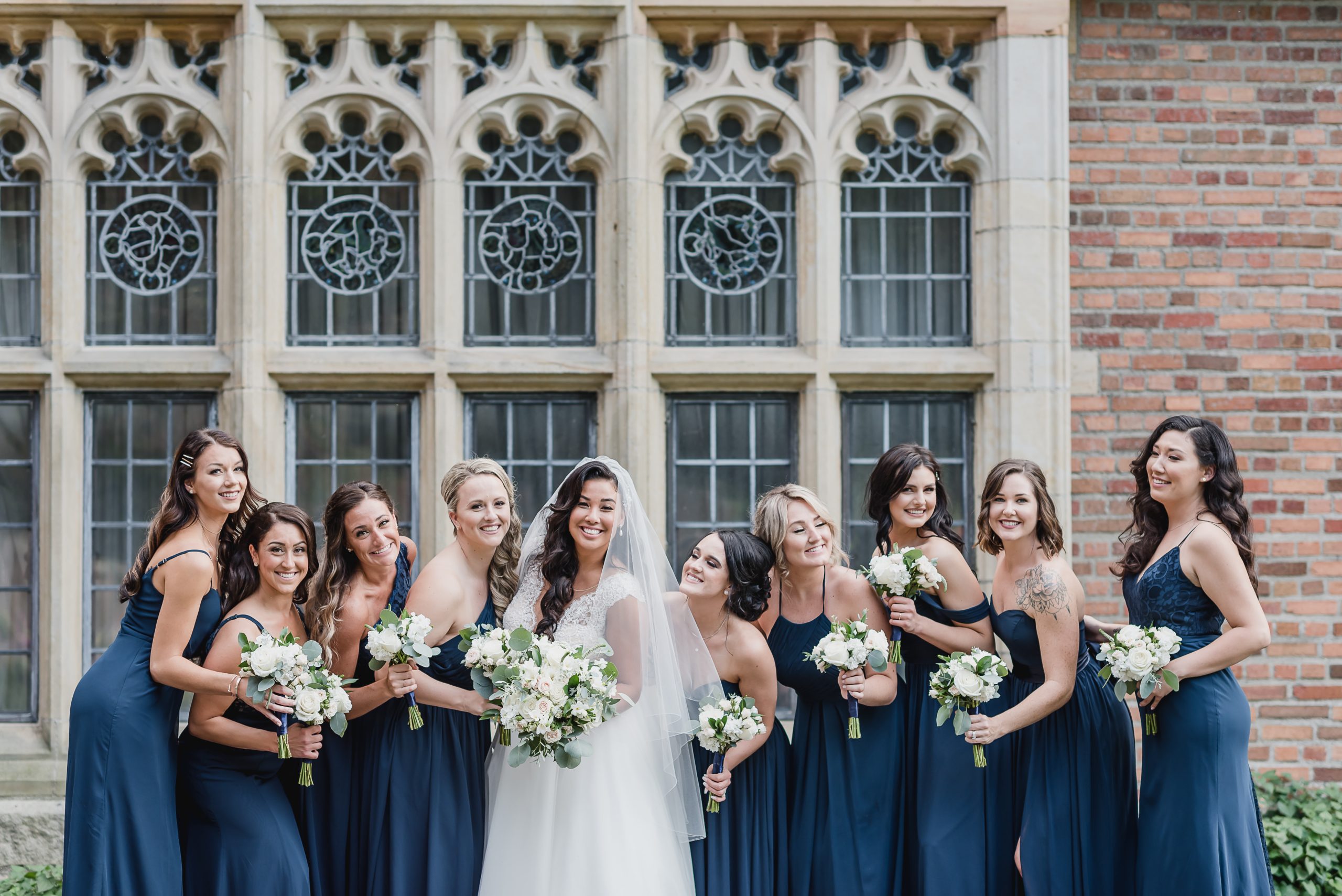 Bride and bridesmaids pose in front of windows at Meadow Brook Hall