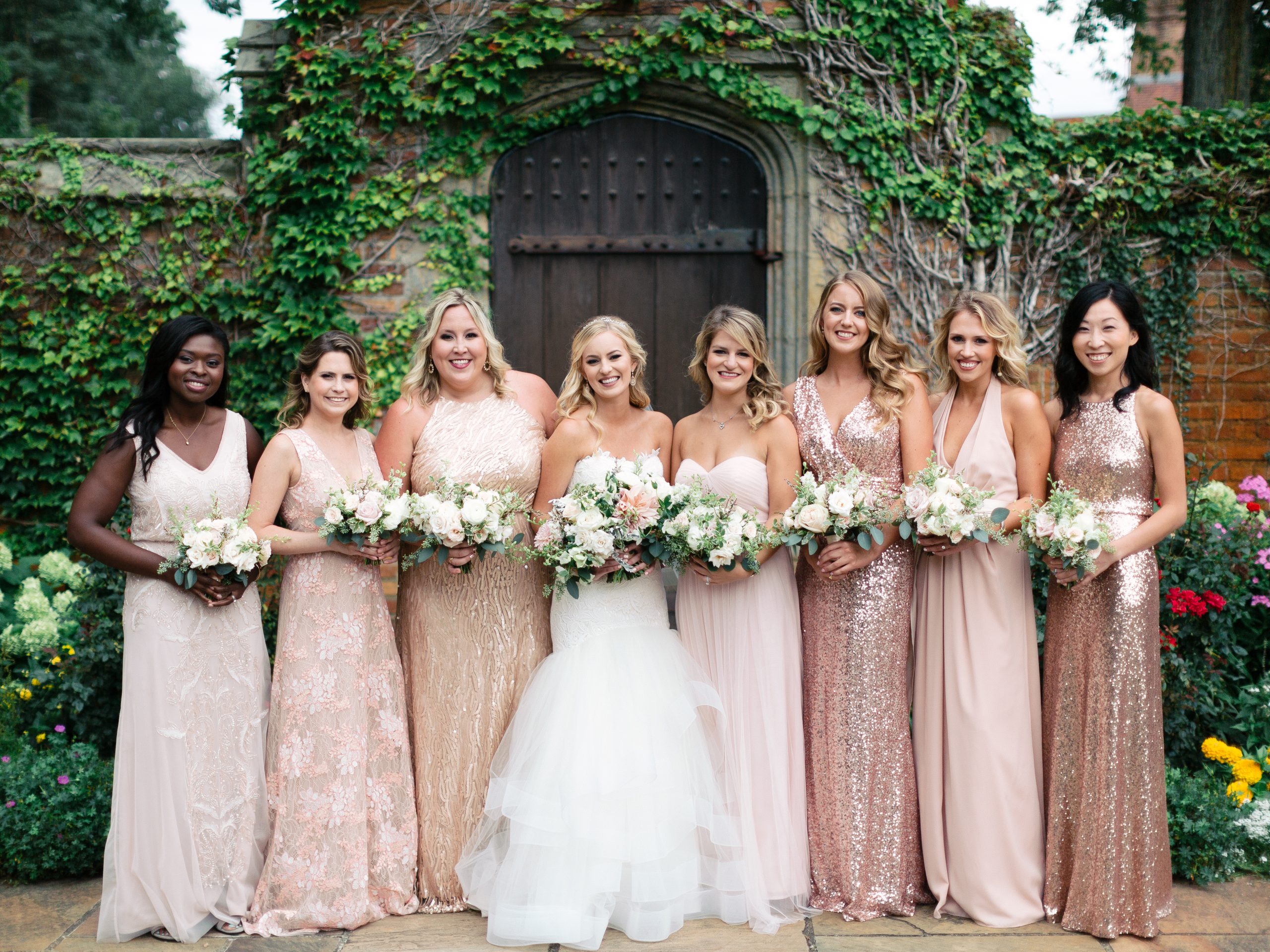 Bridesmaids in pink stand against the garden wall at Meadow Brook