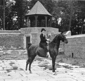 Frances Dodge on horseback near The Tea House and English Garden.