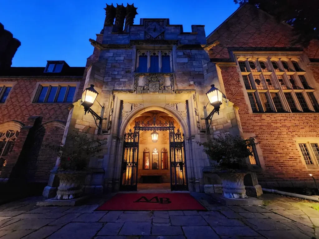 The front facade of Meadow Brook Hall at night in the fall.